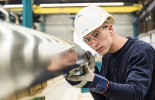a man wearing a hard hat and gloves working on a car